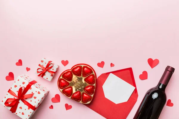 Egy Üveg Vörösbor Színes Háttérrel Valentin Napra Ajándékdobozzal Borítékkal Csokoládéval — Stock Fotó