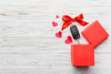 Siyah araba anahtarı, renkli arka planda kırmızı kalp ve kurdele olan hediye kutusunda. Sevgililer Günü Kompozisyonu Üst Görünüm.