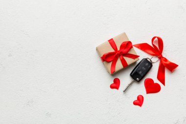 Siyah araba anahtarı, renkli arka planda kırmızı kalp ve kurdele olan hediye kutusunda. Sevgililer Günü Kompozisyonu Üst Görünüm.