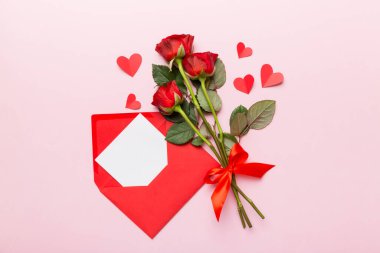 Zarflı sevgililer günü kompozisyonu, gül çiçeği ve kırmızı kalp masada. Üst manzara, düz yatış. Tatil kavramı.