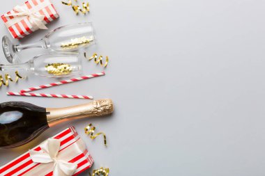 Renkli simli bir şişe şampanya, konfeti ve renkli arka planda metin için hediye kutusu alanı, üst manzara. Komik, noel ve doğum günü kutlaması.