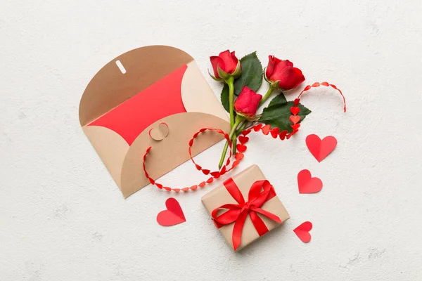 Zarflı sevgililer günü kompozisyonu, gül çiçeği ve kırmızı kalp masada. Üst görünüm, düz görünüm, kopyalama alanı Tatil kavramı.