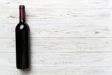 Renkli masada bir şişe kırmızı şarap. Düz konum, üst görünüm kopyalama alanı.