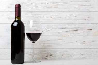 Bir bardak kırmızı şarap ve renkli masada bir şişe. Düz konum, üst görünüm kopyalama alanı.