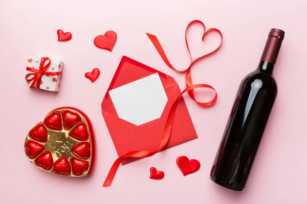 ギフトボックス チョコレートとバレンタインデーのための色の背景に赤ワインのボトル ハート型にチョコレートトップビューのギフトボックス付きコピースペース — ストック写真