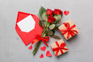 Zarflı sevgililer günü kompozisyonu, gül çiçeği ve kırmızı kalp masada. Üst manzara, düz yatış. Tatil kavramı.