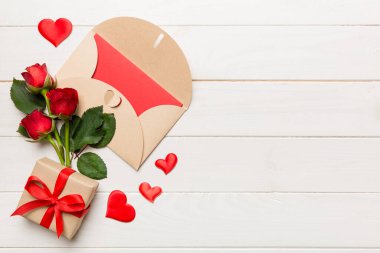 Zarflı sevgililer günü kompozisyonu, gül çiçeği ve kırmızı kalp masada. Üst görünüm, düz görünüm, kopyalama alanı Tatil kavramı.