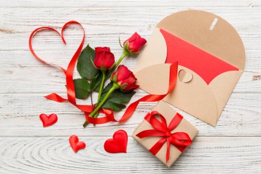 Zarflı sevgililer günü kompozisyonu, gül çiçeği ve kırmızı kalp masada. Üst görünüm, düz görünüm, kopyalama alanı Tatil kavramı.