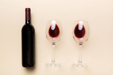 Bir bardak kırmızı şarap ve renkli masada bir şişe. Düz konum, üst görünüm kopyalama alanı.