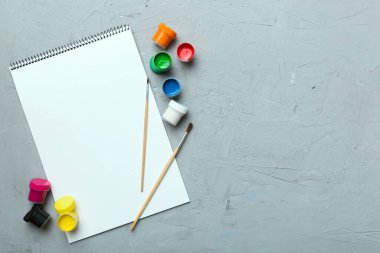 Albüm sayfaları, boyalar, kalemler, renkli arka planda fırçalar. Boşluğu olan üst görünüm. Yaratıcılık için işyeri. ev öğretmenliği kavramı çizimi.
