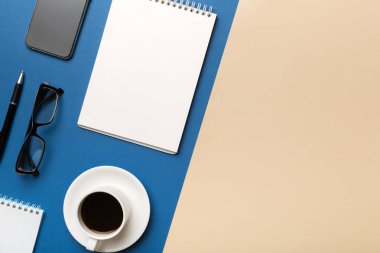 Defterli modern ofis masası ve bir fincan kahveli diğer malzemeler. Tasarım için boş defter sayfası. Üst manzara, düz uzanma.