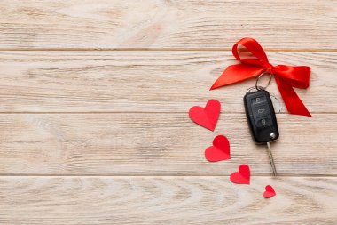 Kırmızı kurdeleli ve renkli masada kalbi olan araba anahtarı. Sevgililer Günü ya da Noel hediyesi vermek, Kopya Alanı ile Üst Görünüm.