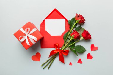 Zarflı sevgililer günü kompozisyonu, gül çiçeği ve kırmızı kalp masada. Üst manzara, düz yatış. Tatil kavramı.