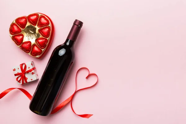 ギフトとチョコレートでバレンタインデーのための色の背景に赤ワインのボトル ハート型にチョコレートトップビューのギフトボックス付きコピースペース — ストック写真