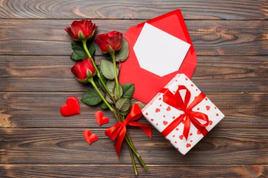 Zarflı sevgililer günü kompozisyonu, gül çiçeği ve kırmızı kalp masada. Üst manzara, düz yatış. Tatil kavramı.