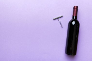 Renkli masada tirbuşonlu bir şişe kırmızı şarap. Düz konum, üst görünüm kopyalama alanı.