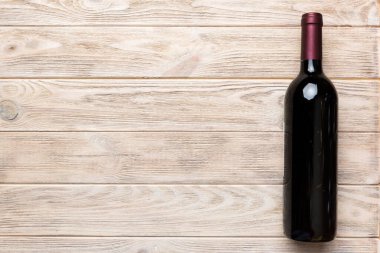 Renkli masada bir şişe kırmızı şarap. Düz konum, üst görünüm kopyalama alanı.