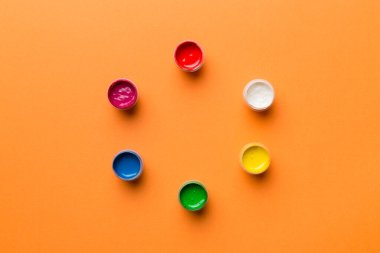 Renkli arka planda farklı renkte gagalı kavanozlar. Hobi resim. Boşluğu olan üst görünüm. Yaratıcılık için işyeri. ev öğretmenliği kavramı çizimi.