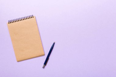 Renkli bir arka planda okul kahverengi defteri, bir masadaki spiral el işi not defteri..