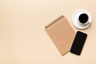 Modern ofis masası, defter, akıllı telefon ve kahve ile birlikte diğer malzemeler. Tasarım için boş defter sayfası. Üst manzara, düz uzanma.