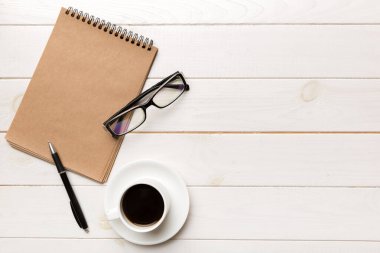 Defterli modern ofis masası ve bir fincan kahveli diğer malzemeler. Tasarım için boş defter sayfası. Üst manzara, düz uzanma.