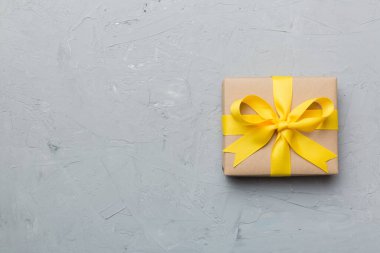 El işi kağıdına sarılı, masa arkasında renkli bir fiyonk olan tatil hediyesi kutusu. Üst görünüm, düz görünüm, kopyalama alanı.