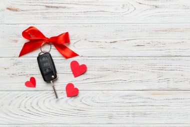 Kırmızı kurdeleli ve renkli masada kalbi olan araba anahtarı. Sevgililer Günü ya da Noel hediyesi vermek, Kopya Alanı ile Üst Görünüm.