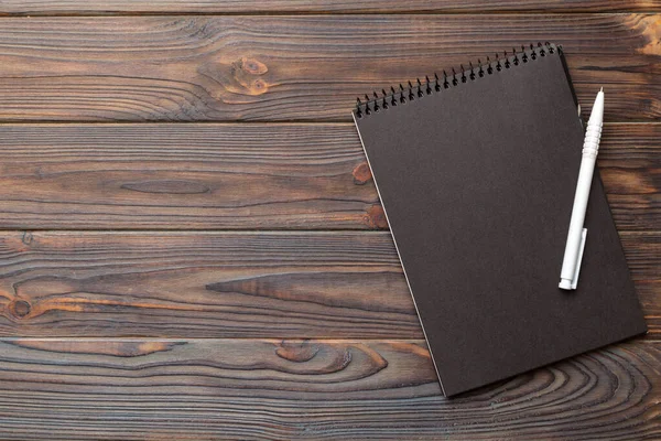 カラーの背景に学校のノート テーブルの上にスパイラルブラックノートパッド Top View — ストック写真