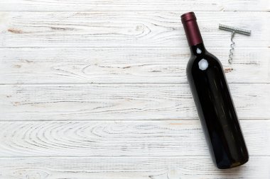 Renkli masada tirbuşonlu bir şişe kırmızı şarap. Düz konum, üst görünüm kopyalama alanı.