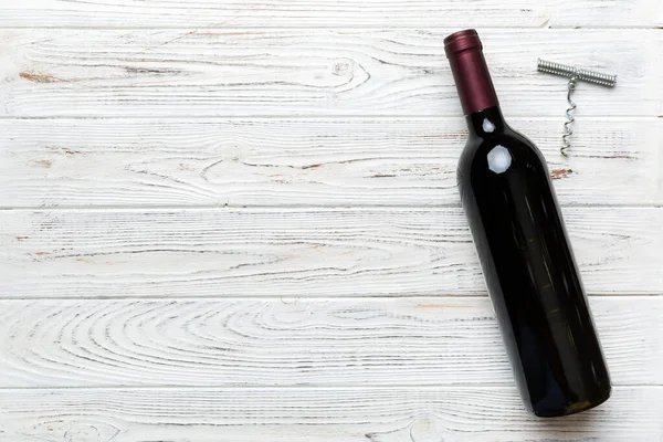 Renkli masada tirbuşonlu bir şişe kırmızı şarap. Düz konum, üst görünüm kopyalama alanı.