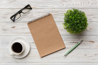 Defterli modern ofis masası ve bir fincan kahveli diğer malzemeler. Tasarım için boş defter sayfası. Üst manzara, düz uzanma.