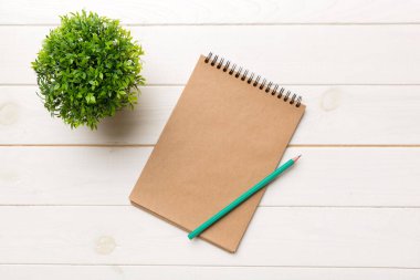 Defterli modern ofis masası ve yeşil ağaçlı diğer malzemeler. Tasarım için boş defter sayfası. Üst manzara, düz uzanma.