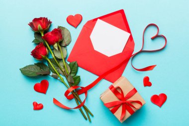 Zarflı sevgililer günü kompozisyonu, gül çiçeği ve kırmızı kalp masada. Üst manzara, düz yatış. Tatil kavramı.