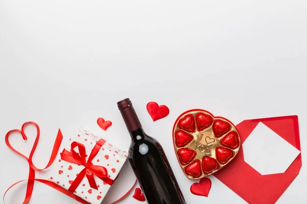 ギフトボックス チョコレートとバレンタインデーのための色の背景に赤ワインのボトル ハート型にチョコレートトップビューのギフトボックス付きコピースペース — ストック写真