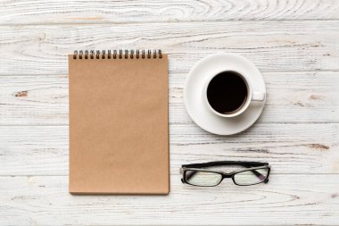 Defterli modern ofis masası ve bir fincan kahveli diğer malzemeler. Tasarım için boş defter sayfası. Üst manzara, düz uzanma.