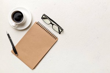 Defterli modern ofis masası ve bir fincan kahveli diğer malzemeler. Tasarım için boş defter sayfası. Üst manzara, düz uzanma.