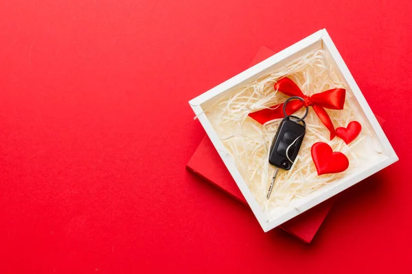 色の背景にリボンと赤の心を持つ現在のボックス内の黒い車のキー バレンタインデーの構図 Top View — ストック写真