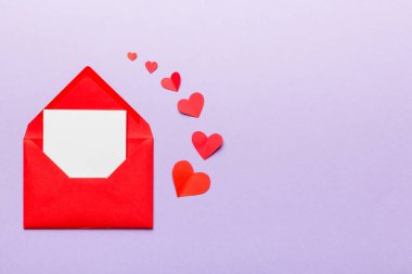 Renkli arka planda beyaz kart ve kalp olan kırmızı kağıt zarf. Top view Sevgililer Günü konsepti.