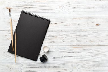 Albüm sayfaları, boyalar, kalemler, renkli arka planda fırçalar. Boşluğu olan üst görünüm. Yaratıcılık için işyeri. ev öğretmenliği kavramı çizimi.