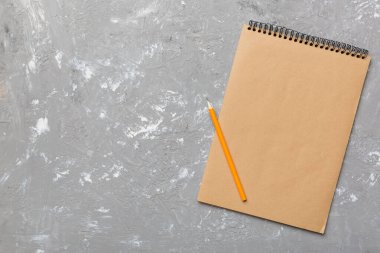 Renkli bir arka planda okul kahverengi defteri, bir masadaki spiral el işi not defteri..