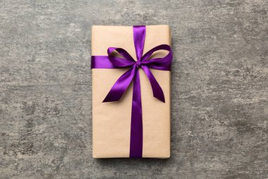 El işi kağıdına sarılı, masa arkasında renkli bir fiyonk olan tatil hediyesi kutusu. Üst görünüm, düz görünüm, kopyalama alanı.