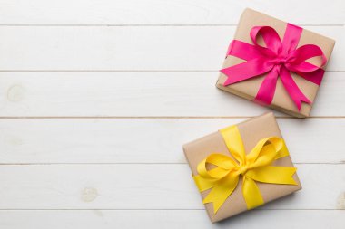 El işi kağıdına sarılı, masa arkasında renkli bir fiyonk olan tatil hediyesi kutusu. Üst görünüm, düz görünüm, kopyalama alanı.