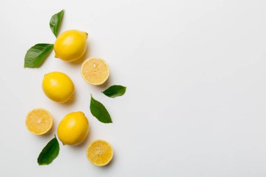 Renkli arka planda yeşil yapraklı taze limonlar, üst görünüm, metin için boşluk.