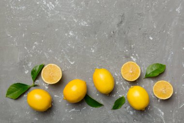 Renkli arka planda yeşil yapraklı taze limonlar, üst görünüm, metin için boşluk.