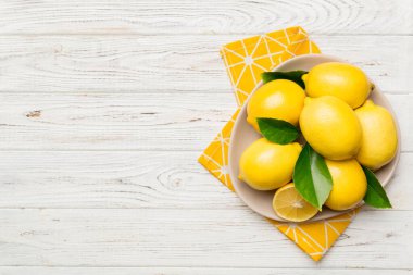 Taze kesilmiş limon ve tüm limonları renkli arka planda yuvarlak tabakta. Yemek ve içecek malzemeleri hazırlanıyor. Sağlıklı beslenme teması üst görünüm kopyalama alanı.