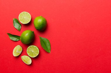 Yeşil yapraklı kireç meyveleri ve beyaz arka planda yarım dilim kesilmiş. Üst Manzara. Kopyalama alanı olan düz.