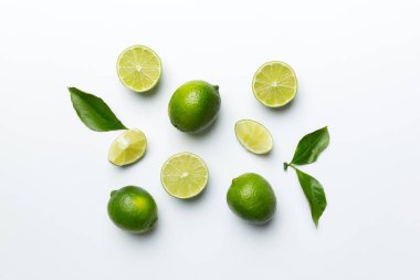 Yeşil yapraklı kireç meyveleri ve beyaz arka planda yarım dilim kesilmiş. Üst Manzara. Kopyalama alanı olan düz.