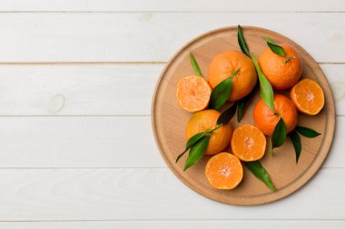 Taze kesilmiş mandalinalar ve renkli arka planda yuvarlak tabaklar. Yemek ve içecek malzemeleri hazırlanıyor. Sağlıklı beslenme teması üst görünüm kopyalama alanı.