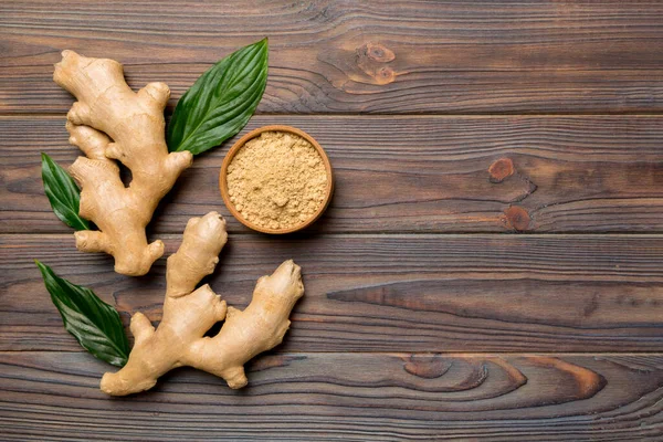 Finely dry Ginger powder in bowl with green leaves isolated on colored background. top view flat lay.