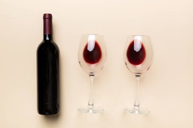 Bir bardak kırmızı şarap ve renkli masada bir şişe. Düz konum, üst görünüm kopyalama alanı.